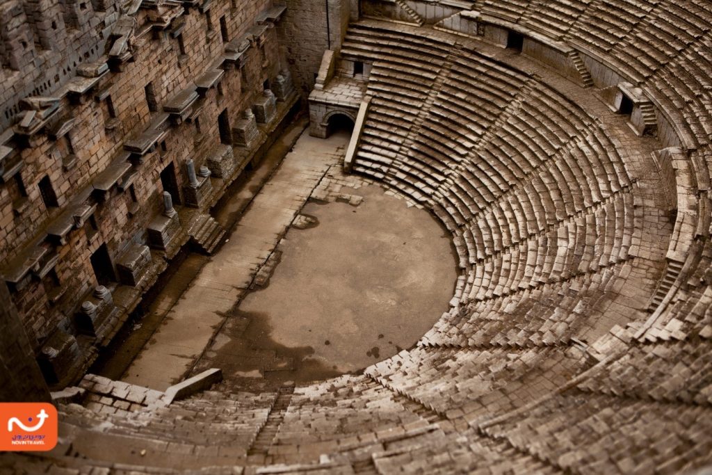 نمای نزدیک از آمفی‌تئاتر آسپندوس، با پله‌های منحنی و فضایی تاریخی.