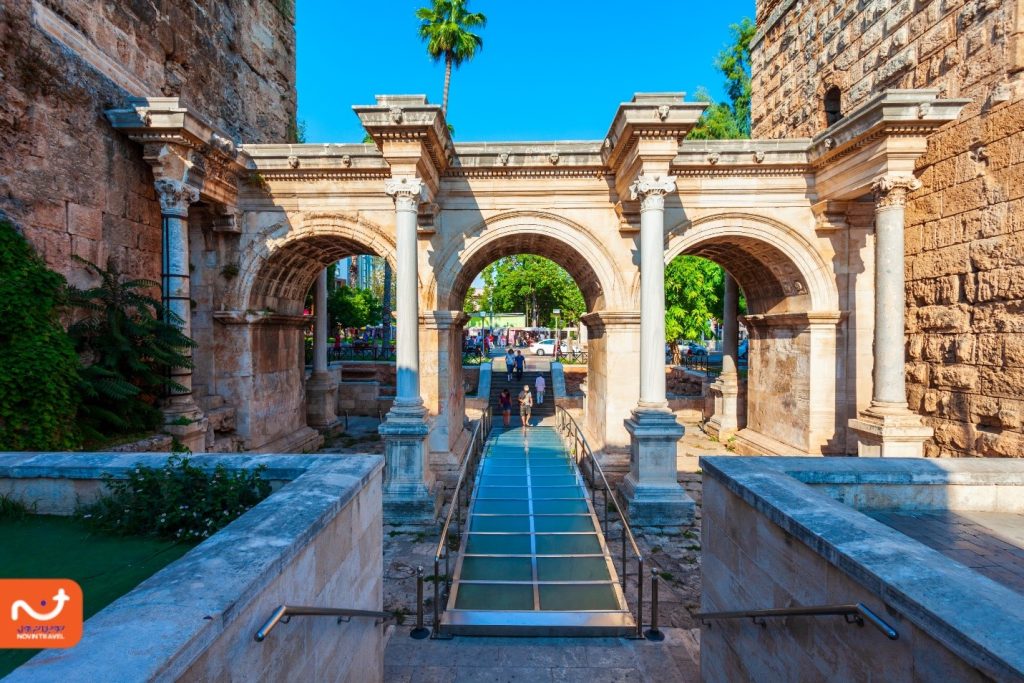 طاق تاریخی و باستانی با معماری سنگی و ستون‌های زیبای شهر قدیمی کالیچی، در محیطی سرسبز و آفتابی.