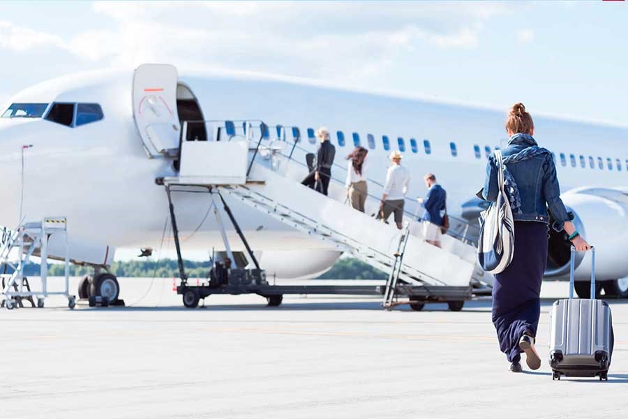 تصویری از شخصی که برای سوار شدن به هواپیما به سمت هواپیما حرکت می‌کند.