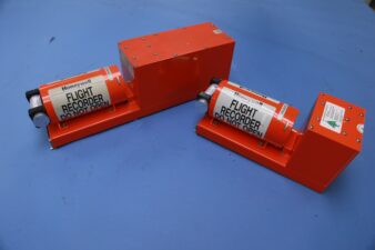 دو جعبه سیاه هواپیما در شرایط سالم روی یک میز آبی، برچسب‌گذاری‌شده با "Flight Recorder - Do Not Open".