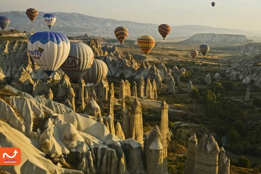 "دره عشق از جاهای دیدنی کاپادوکیا با ستون‌های سنگی خاص و بالن‌های زیبا در آسمان."